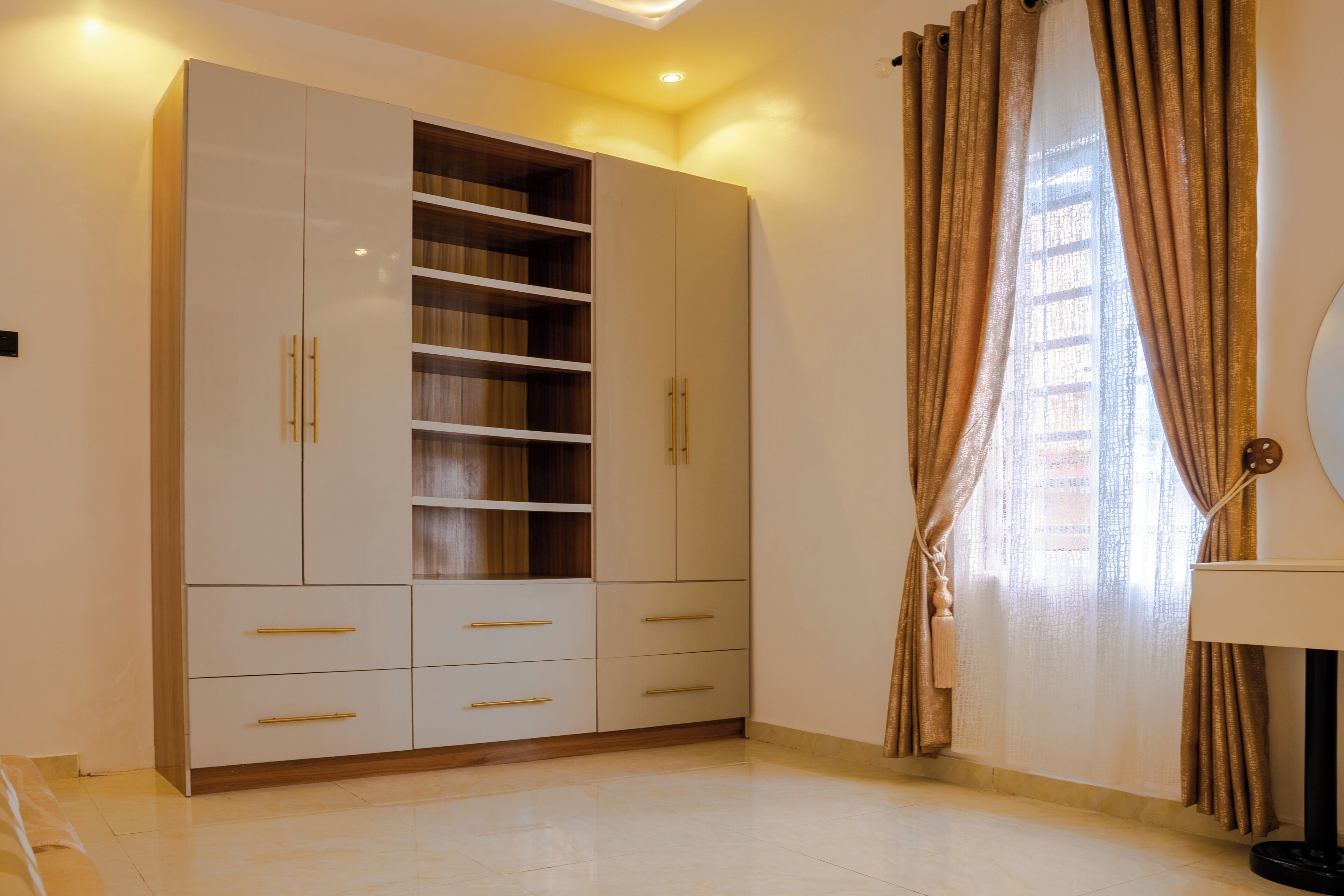 Una habitació amb un armari gran, un llit i una finestra amb cortines.