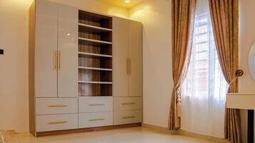 Una habitació amb un armari gran, un llit i una finestra amb cortines.