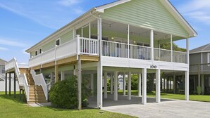 Ein zweistöckiges Haus mit überdachter Veranda und einer Treppe, die zum oberen Stockwerk führt.