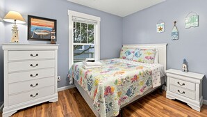 Ein Schlafzimmer mit Bett, Schminktisch, Nachttisch, Fenster und Wanddekorationen.