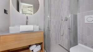 A modern bathroom with a glass-enclosed shower, a round mirror, and a wooden vanity. - Villa Rovni (Rasa)
