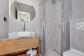 A modern bathroom with a glass-enclosed shower, a round mirror, and a wooden vanity. - Villa Rovni (Rasa)