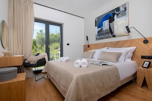 Ein Hotelzimmer mit Bett, Schreibtisch, Stuhl, einem Fenster mit Vorhängen und einem Bild an der Wand.