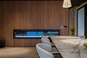 A modern meeting room with a long table, comfortable chairs, a built-in fireplace, and a pendant light. - Villa She Luxury (Groznjan)