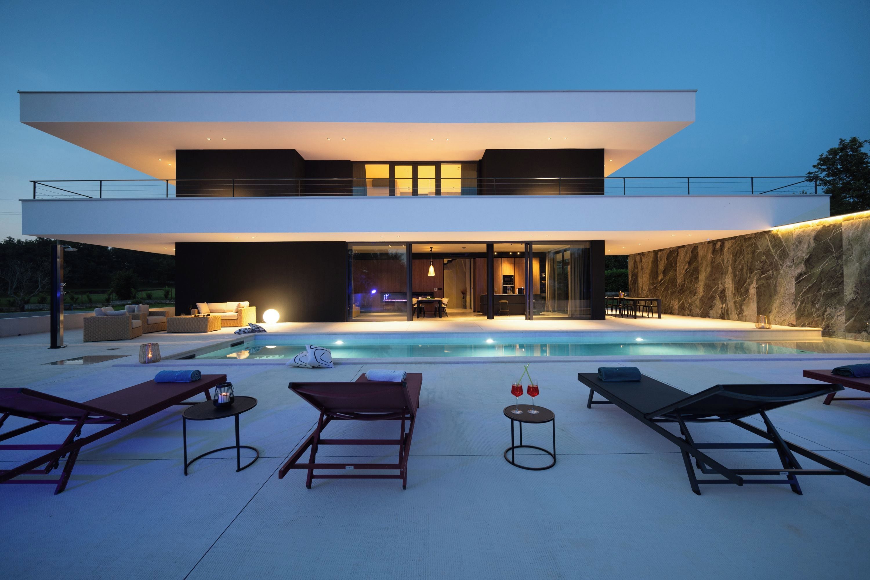 Une maison moderne à deux étages, dotée d’une piscine, d’un espace extérieur aménagé et offrant une vue sur l’intérieur.