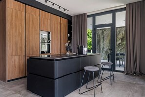 Eine moderne Küche mit Holzschränken, einer schwarzen Arbeitsplatte und einer großen Kochinsel mit Barhocker.