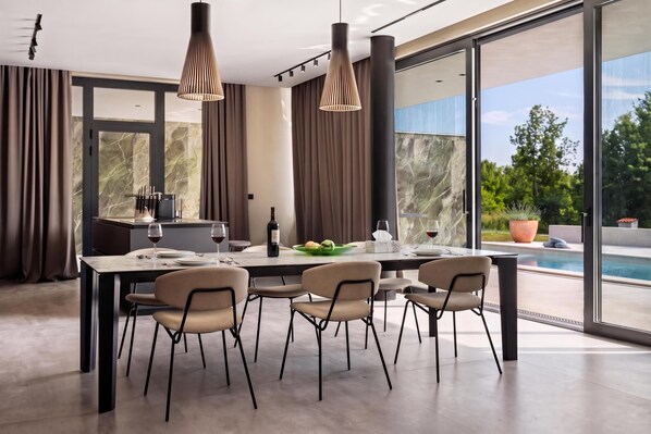 A modern dining area with a large table, chairs, and pendant lighting. - Villa She Luxury (Groznjan)