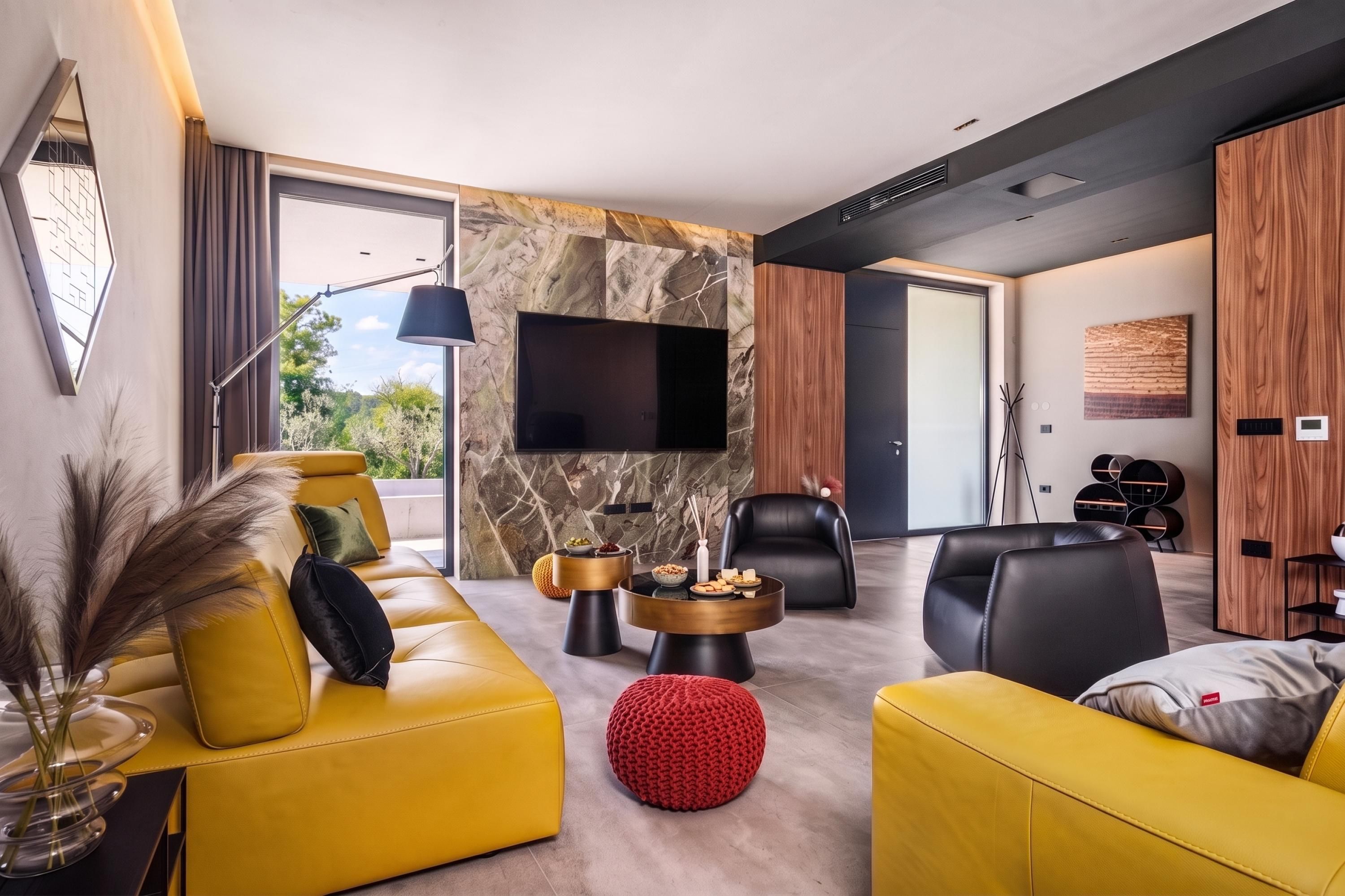 Un salon moderne avec un canapé jaune, un pouf rouge, un fauteuil en cuir noir et un téléviseur à écran plat fixé à un mur en pierre.