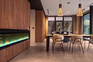 Ein moderner Essbereich mit einer langen Holzwand, einem eingebauten Aquarium und einem großen Fenster mit Blick ins Freie.