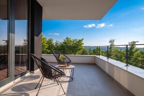 Een balkon met twee stoelen en een klein tafeltje, met uitzicht op een schilderachtig landschap.