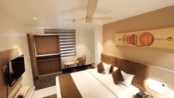 A hotel room with a bed, a desk, a chair, a television, and a ceiling fan.