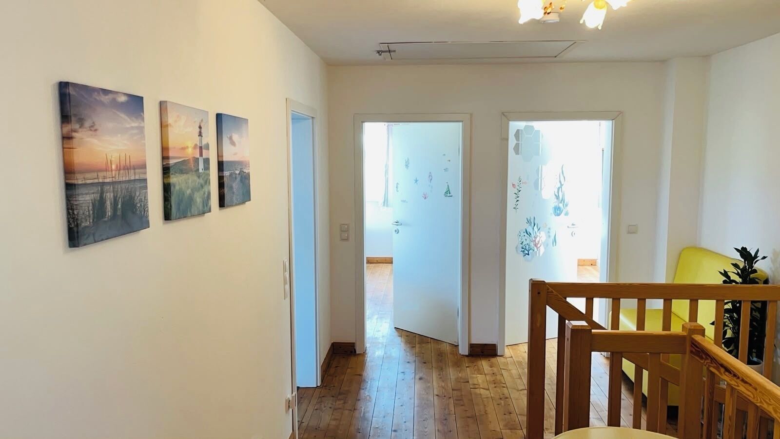 A hallway with wooden flooring, a staircase, and a yellow chair.