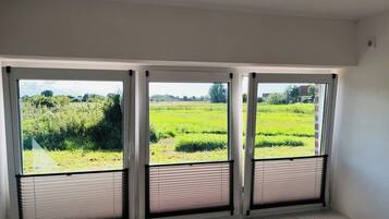 Una habitación con tres ventanas amplias que ofrecen vista a un campo verde.