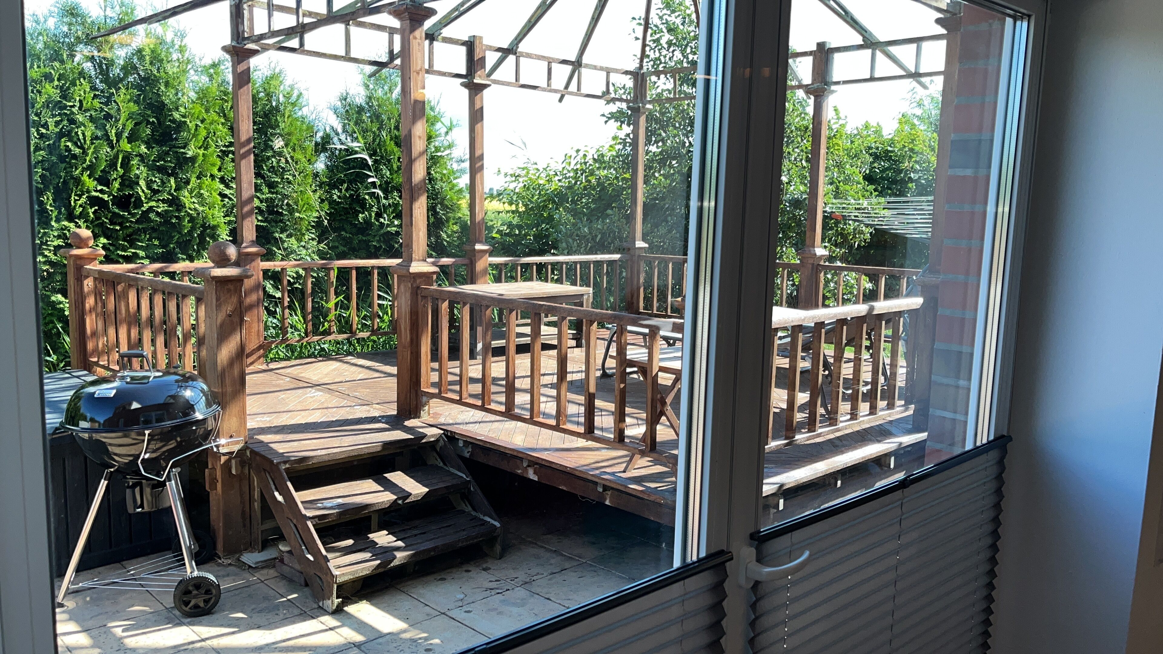 Une terrasse en bois avec un barbecue et du mobilier d’extérieur.