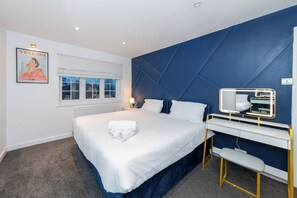 Ein Schlafzimmer mit Bett, Nachttisch und Schreibtisch mit Spiegel.