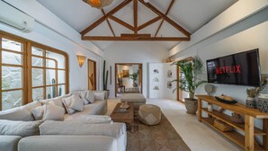 Ein modernes Wohnzimmer mit einer großen Couch, einem Couchtisch und einem an der Wand befestigten Fernseher.