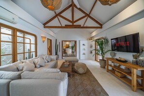 Ein modernes Wohnzimmer mit einer großen Couch, einem Couchtisch und einem an der Wand befestigten Fernseher.