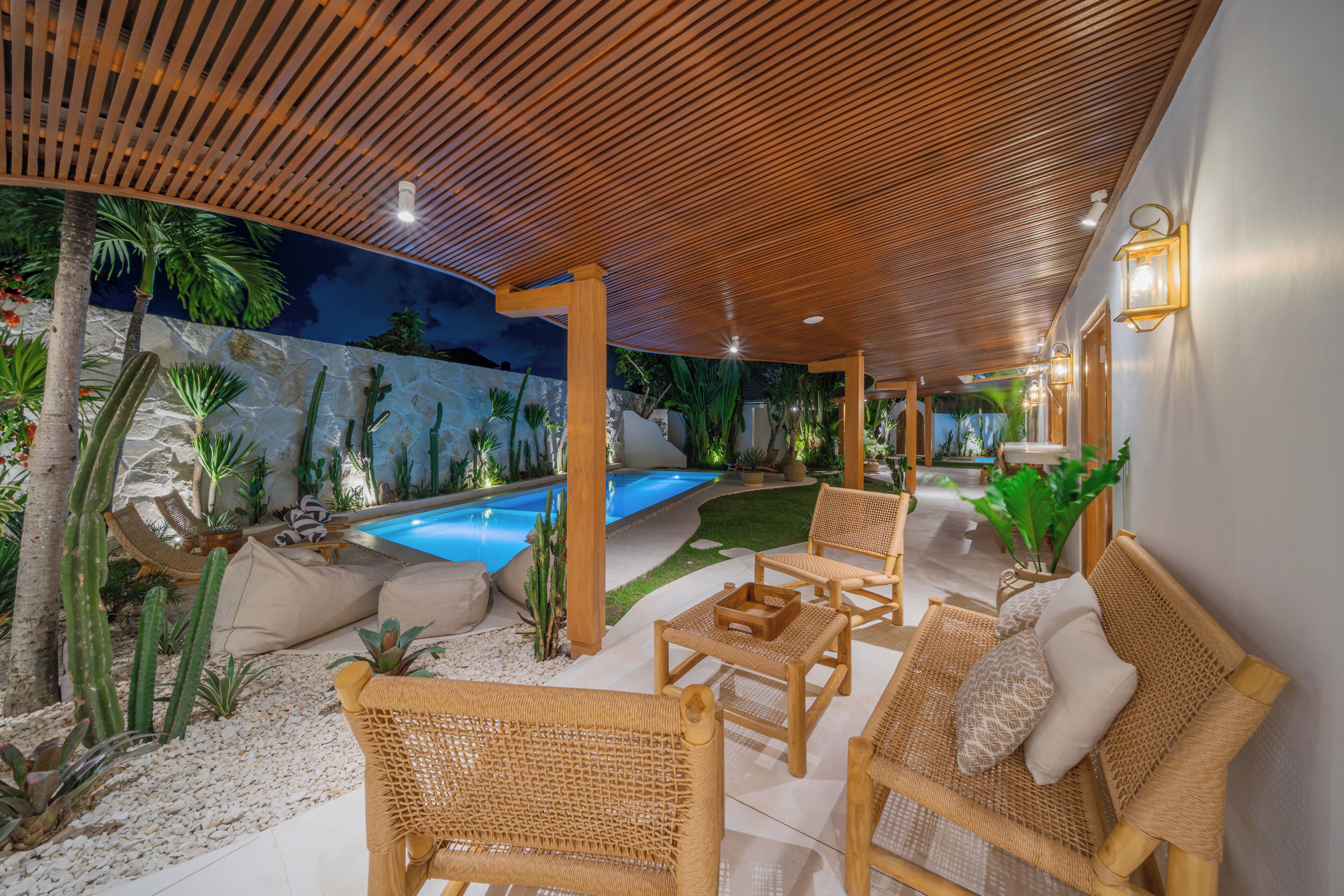 A poolside area with wicker furniture, a pool, and a wooden ceiling.