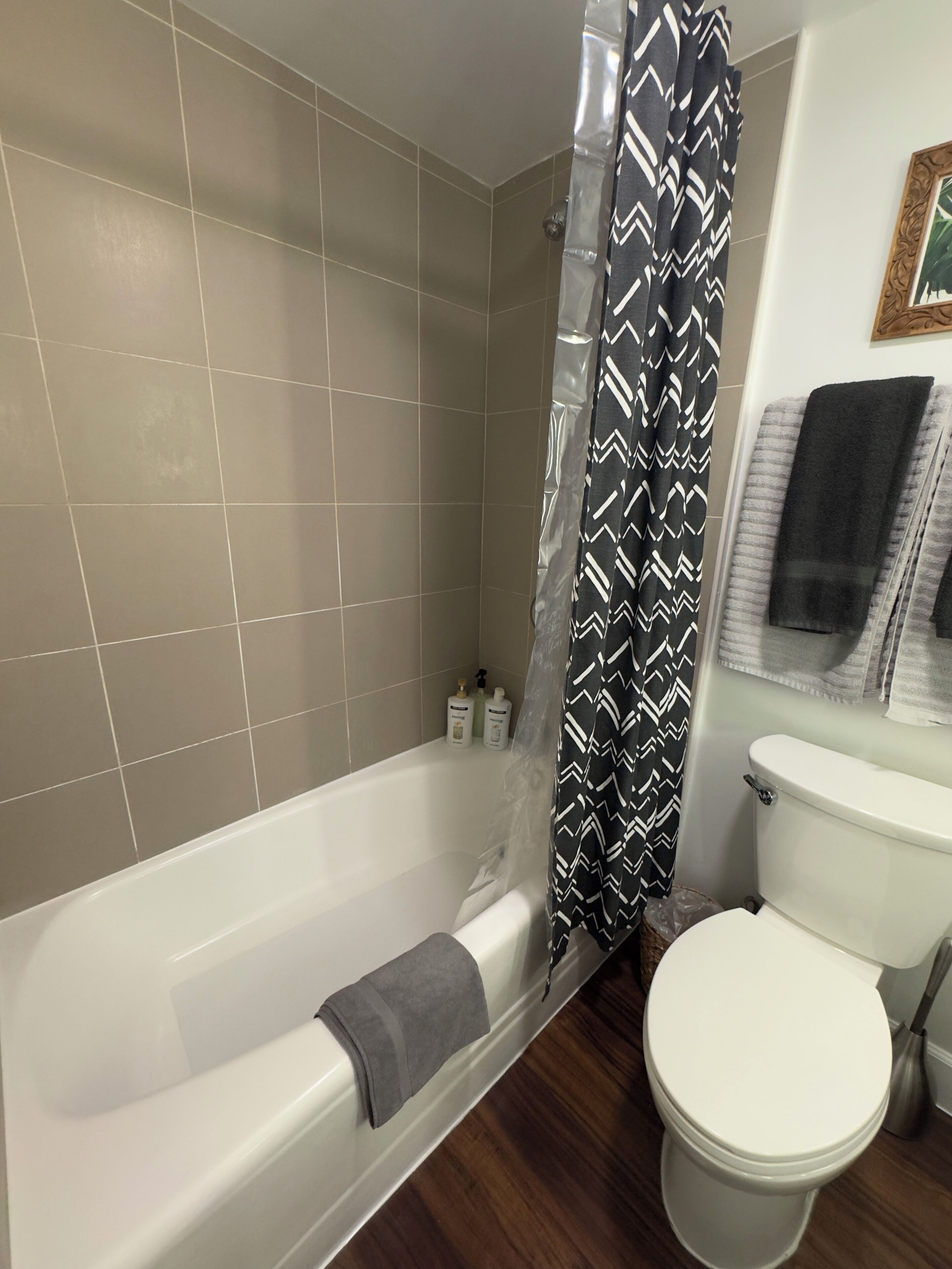 A bathroom with a bathtub, toilet, and shower curtain.