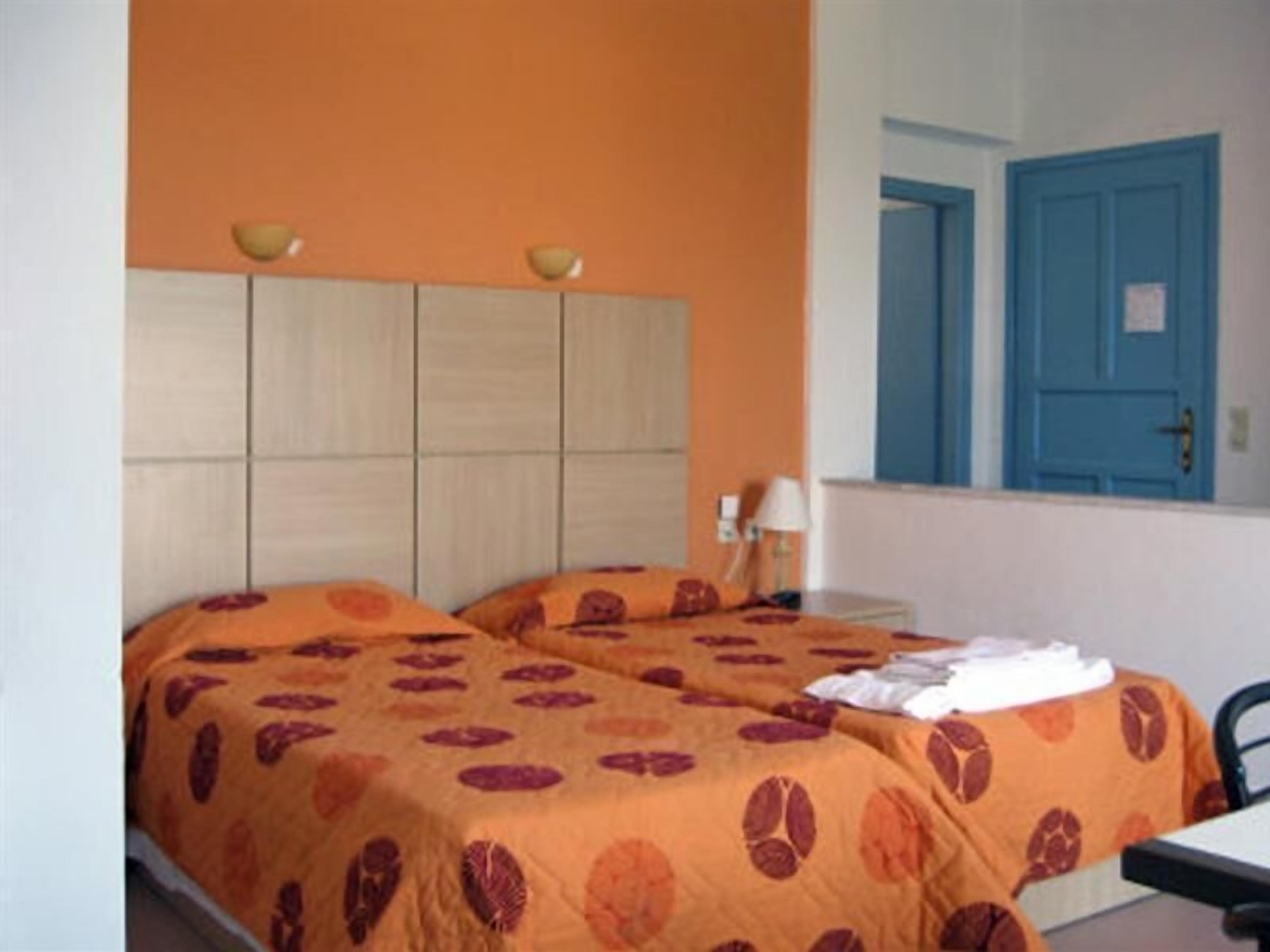 A room with a bed, a nightstand, a lamp, and a blue door.
