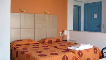 A room with a bed, a nightstand, a lamp, and a blue door.