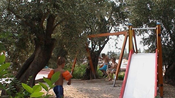 A playground with a slide and swings, surrounded by trees. - Lassia Hotel (Lesvos)