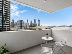 Ein Balkon mit Blick auf eine Stadtansicht, einem runden Tisch und zwei Stühlen.