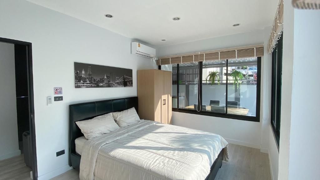 A bedroom with a bed, a wardrobe, a cityscape picture, and a window with a view.