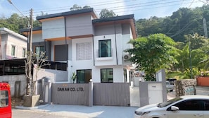 A modern two-story building with a gated entrance, a sign reading 'DANAN CO. LTD.', and a parked car in front. - GREEN HILLS VILLAS - Dan An House (TAMBON PATONG)