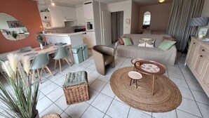 Uma sala de estar moderna com um sofá, um espaço de refeições com cadeiras, uma cozinha com armários e um espelho grande na parede.