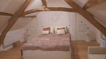 A bedroom with a vaulted ceiling, a bed with multiple pillows, and decorative wall art.