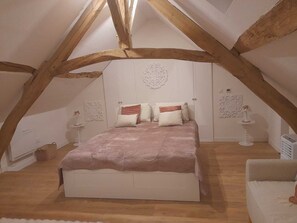 Een slaapkamer met een gewelfde plafond, een bed met veel kussens en decoratieve wandkunst.