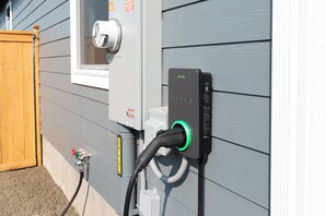 Un cuadro eléctrico exterior con una luz indicadora verde, una ventana blanca y una pared gris.