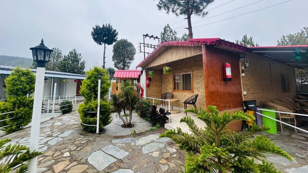 A wooden cabin with a red roof, stone pathway, and potted plants.