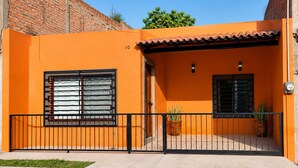 Un edificio residencial con fachada de ladrillo, techo de tejas y un patio delantero cercado.