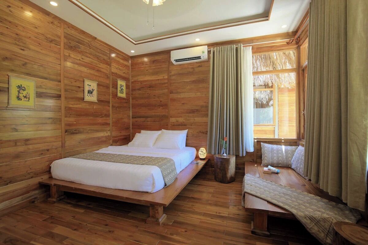A wooden-paneled room with a bed, bedside table, and a window with curtains.