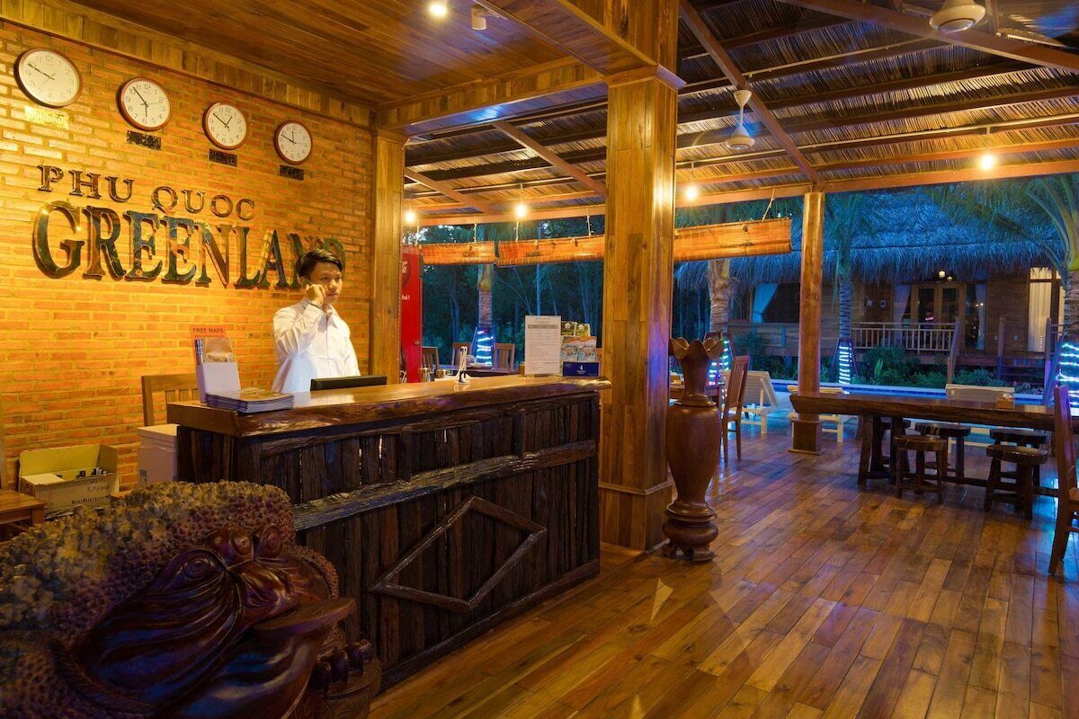 A restaurant interior with a wooden bar, a chef, and a tropical view.