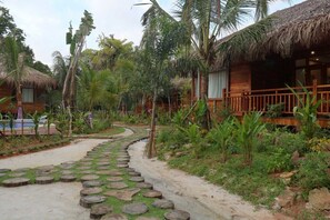 A tropical resort with thatched-roof cabins, a paved pathway, and lush greenery. - Phu Quoc Green Land Resort (Phu Quoc)