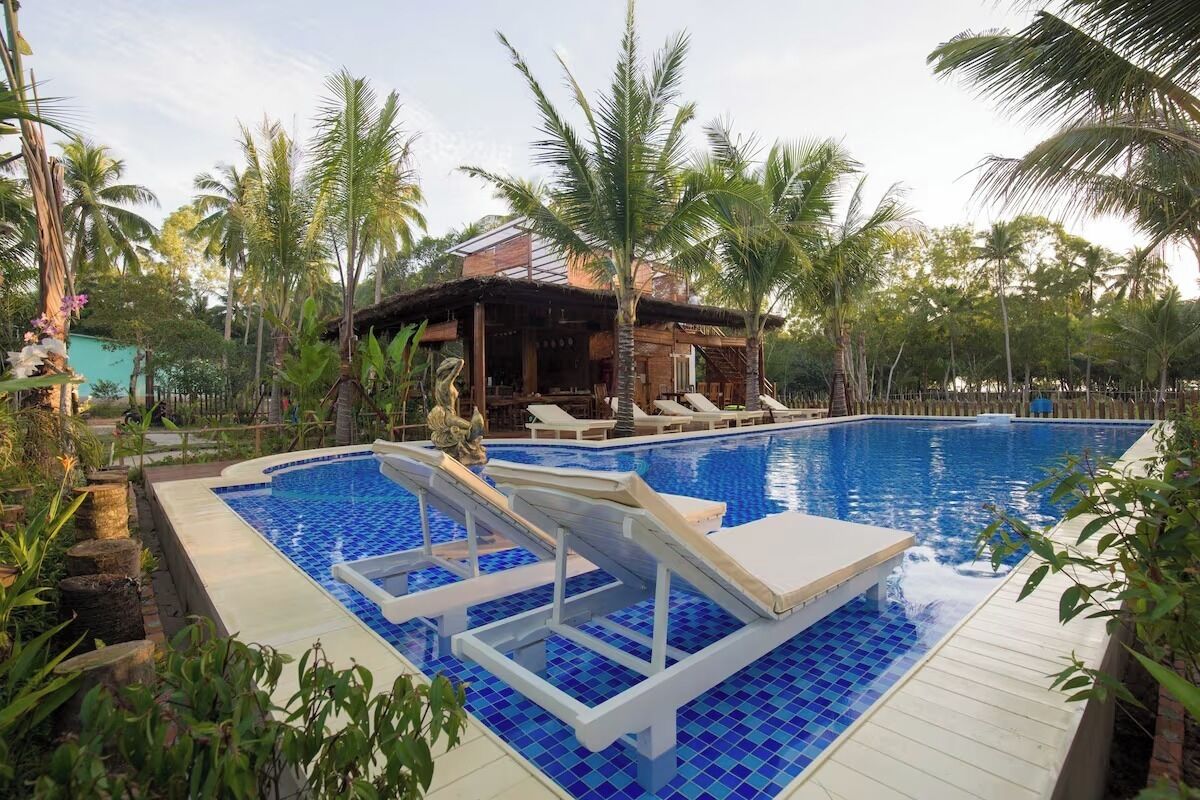 Une piscine avec des chaises longues et un petit bâtiment en arrière-plan.