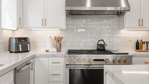 A modern kitchen with white cabinetry, stainless steel appliances, and a gas stove. - NEW: Fun on 4th Encinitas (Aug 2026) rooftop fire pit (Encinitas)