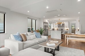 Ein modernes Wohnzimmer mit einer Couch, einem Couchtisch und Blick auf den Küchenbereich.