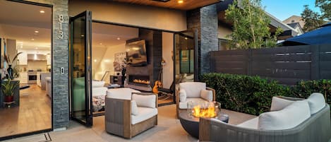 An outdoor living area with a fire pit, seating, and a view into the house.