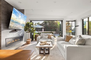 A modern living room with a fireplace, comfortable seating, and a large TV mounted on the wall.