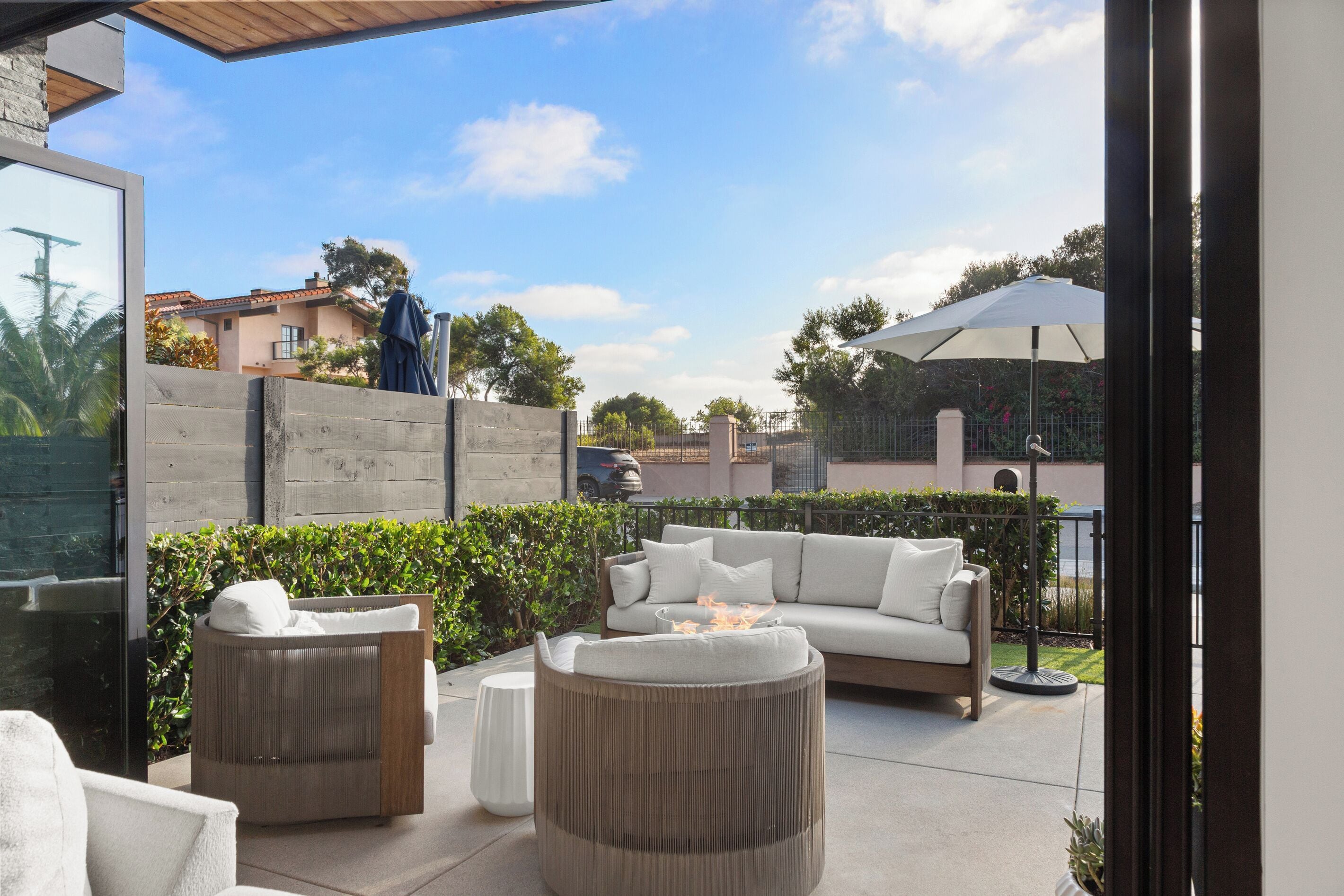 An outdoor patio area with a sofa, two chairs, and a round table.