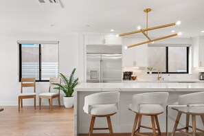 A modern kitchen with a central island, stainless steel appliances, and a pendant light fixture.