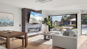 A modern living room with a fireplace, a large TV, and a comfortable seating area. - NEW: Fun on 4th Encinitas (Aug 2026) rooftop fire pit (Encinitas)