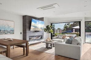 Ein modernes Wohnzimmer mit Kamin, großem Fernseher und einer gemütlichen Sitzecke.