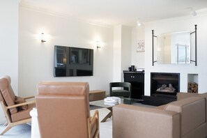 Ein modernes Wohnzimmer mit Flachbildfernseher, Kamin und zwei Sesseln.