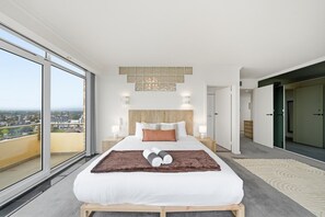 A modern bedroom with a large bed, a view of the city, and a sliding door closet. - The Penthouse | Spa, Sauna, Gym, 360° Views, 4BR (Glenelg North)