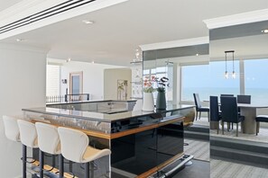 Eine moderne Küche mit Kochinsel, Barhocker und Meerblick.